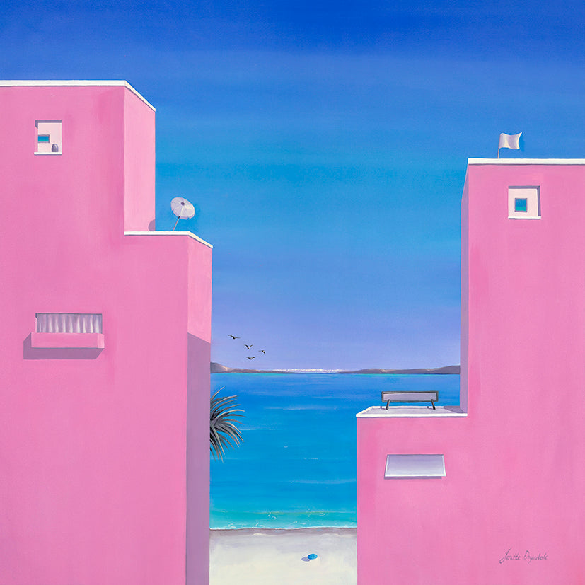 Two pink buildings set against the backdrop of the turquoise ocean. The clouds in the distance touch the mountains and the sea. The palm tree, birds and umbrella add to the scene. 